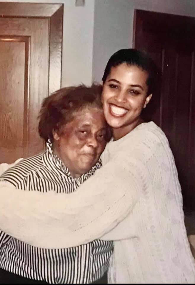 Kimberly Craig in white sweater hugging her grandmother who is wearing a black stripped shirt.